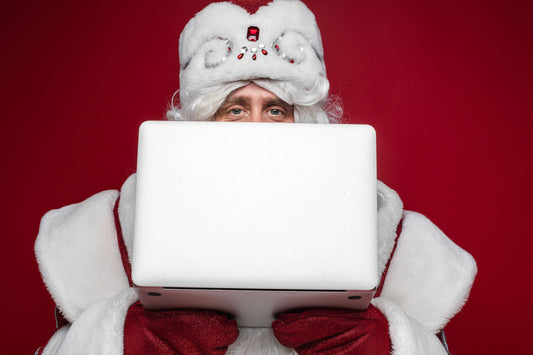 Secret Santa Blog - a man in a white hat and beard is staring directly into the camera with a laptop in hand - signifying online Christmas gift exchanges, most likely Secret Santa